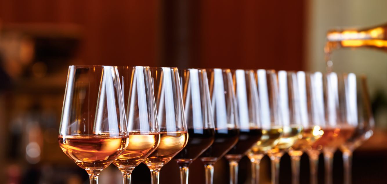 A row of wine glasses being filled at a bar